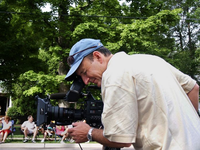 a cameraman bending over a camera focusing and framing a shot