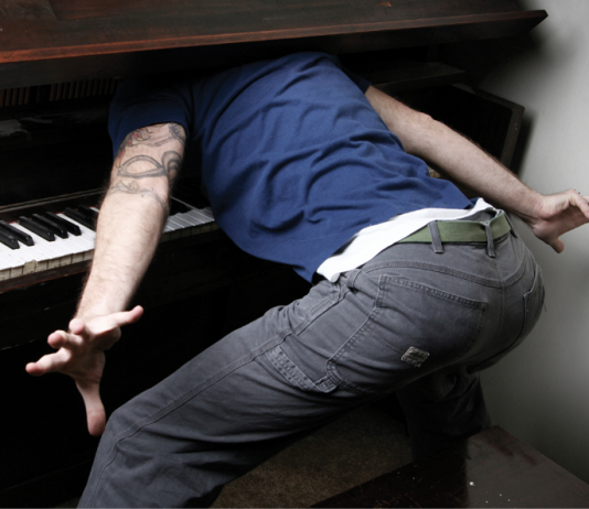 Man with head stuck in piano cover
